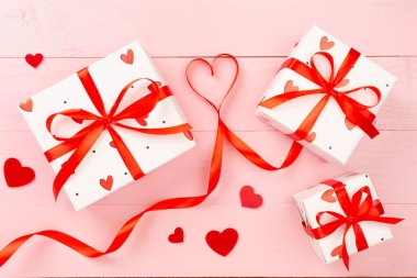 Ahşap zemin üzerinde kırmızı kalpler olan hediye kutuları, üst görünüm