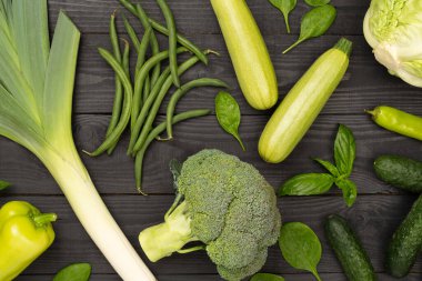 Ahşap arka planda farklı yeşil sebzeler.