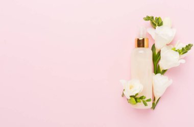 İlaç veya kozmetik ürünlerini damgalamak için beyaz sıkma tüpü. Krem, jöle, cilt bakımı, nemlendirici. Kozmetik boş şişe maketi ve pembe arka planda leylak çiçekleri. Ön görünüm.