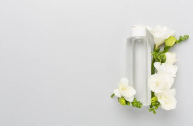 Renkli arka planda frezya çiçekleri olan kozmetik şişesi, üst görünüm