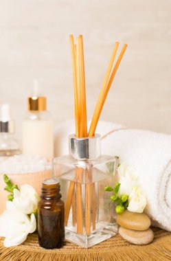 Tahta masa üzerinde frezya çiçeği ve aroma yayıcı içeren spa kompozisyonu