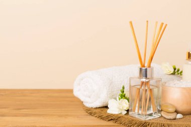 Tahta masa üzerinde frezya çiçeği ve aroma yayıcı içeren spa kompozisyonu