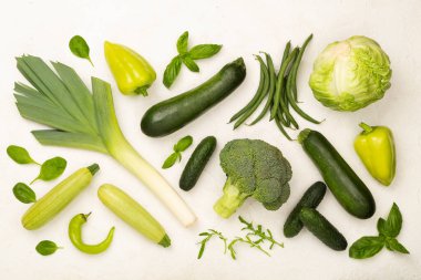 Beton arka planda farklı yeşil sebzeler, üst manzara.