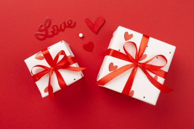 Renkli arka planda kırmızı kalpler olan hediye kutuları, üst görünüm