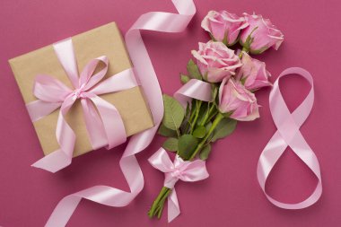 Pembe güllü kompozisyon, hediye kutusu ve arka planda sekizli kurdele, üst manzara. Kadınlar Günü konsepti