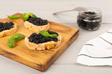 Tahta masada servis edilen siyah havyarlı ekmek dilimi.