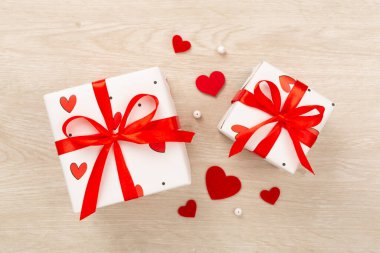 Ahşap zemin üzerinde kırmızı kalpler olan hediye kutuları, üst görünüm