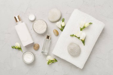 Beton zemin üzerinde spa ürünleri ve çiçeklerle yatıyordu