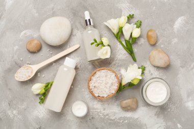 Beton zemin üzerinde spa ürünleri ve çiçeklerle yatıyordu