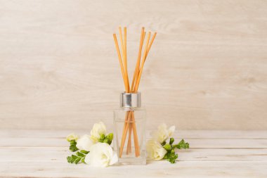 Tahta masa üzerinde frezya çiçeği ve aroma yayıcı içeren spa kompozisyonu