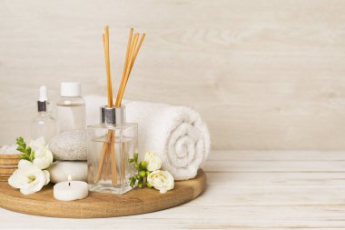 Tahta masa üzerinde frezya çiçeği ve aroma yayıcı içeren spa kompozisyonu