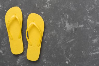 Beton arka planda parlak sarı parmak arası terlikler, üst manzara. Yaz konsepti