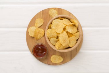 Ahşap arka planda iştah açıcı patates cipsi.