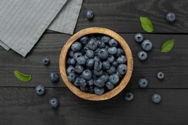 Ahşap arka planda taze yaban mersinli kase, üst manzara.