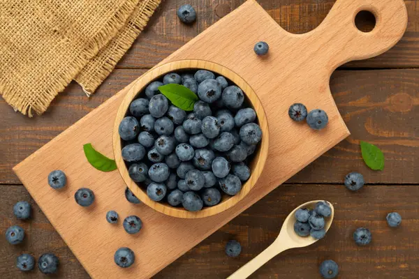 Ahşap arka planda taze yaban mersinli kase, üst manzara.