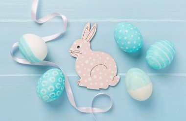 Ahşap arka planda tavşanlı mavi paskalya yumurtaları.