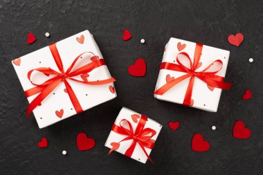 Beton zemin üzerinde kırmızı kalpler olan hediye kutuları, üst görünüm