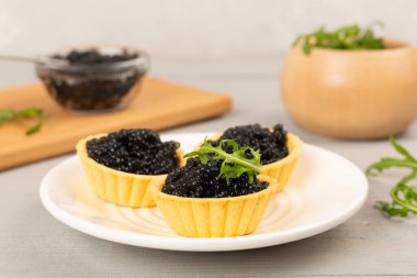 Tahta masada servis edilen siyah havyarlı turtalar.