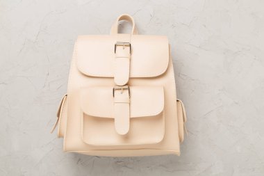 Beton zemin üzerinde bej renkli stil sırt çantası, üst görünüm.