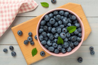 Ahşap arka planda taze yaban mersinli kase, üst manzara.