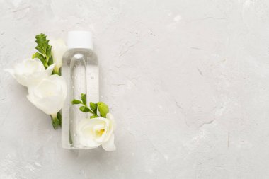 Beton arka planda çiçekli kozmetik şişesi, üst görünüm