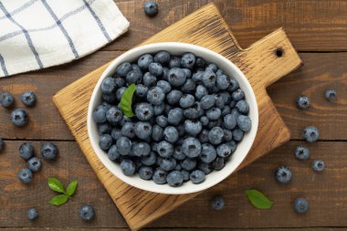 Ahşap arka planda taze yaban mersinli kase, üst manzara.