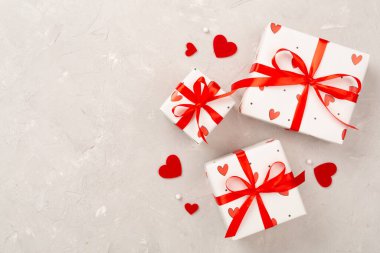 Beton zemin üzerinde kırmızı kalpler olan hediye kutuları, üst görünüm