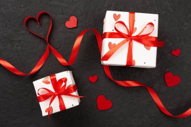 Beton zemin üzerinde kırmızı kalpler olan hediye kutuları, üst görünüm