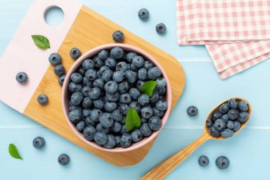 Ahşap arka planda taze yaban mersinli kase, üst manzara.