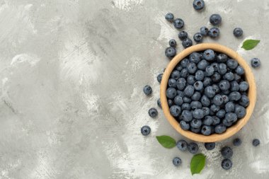 Beton arka planda taze yaban mersinli kase, üst manzara.