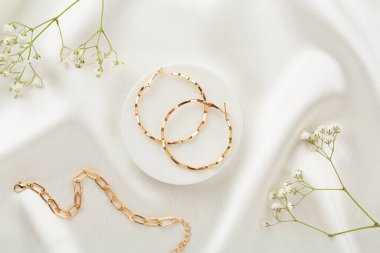 Tekstil arka planında süslemeleri olan zarif altın mücevherler.