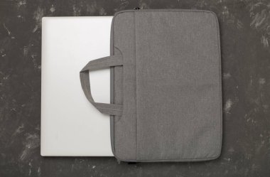 Ahşap arka planda aygıtı olan gri renkli dizüstü bilgisayar çantası, üst görünüm