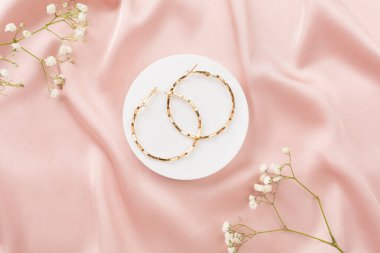 Tekstil arka planında süslemeleri olan zarif altın mücevherler.