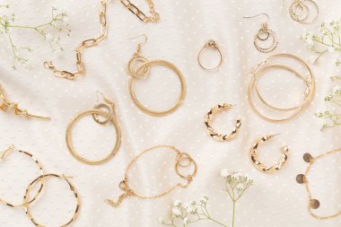 Tekstil arka planında süslemeleri olan zarif altın mücevherler.