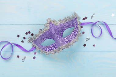 Ahşap arka planda konfetisi olan parlak bir karnaval maskesi.