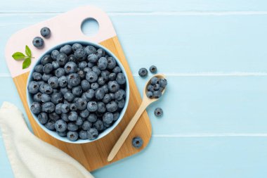 Ahşap arka planda taze yaban mersinli kase, üst manzara.