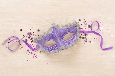 Ahşap arka planda konfetisi olan parlak bir karnaval maskesi.
