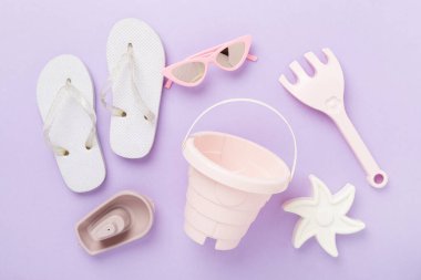 Çocuk terlikleri ve arka planda plaj oyuncakları, üst manzara.