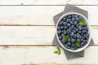 Ahşap arka planda taze yaban mersinli kase, üst manzara.