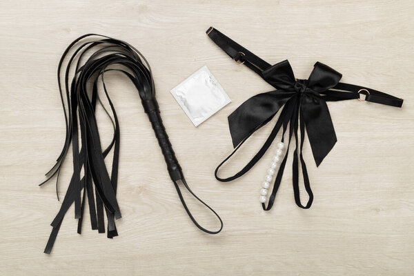 Set of erotic BDSM accessories on wooden background, top view
