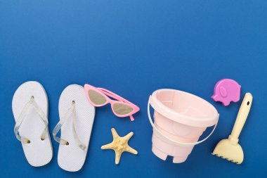 Çocuk terlikleri ve arka planda plaj oyuncakları, üst manzara.