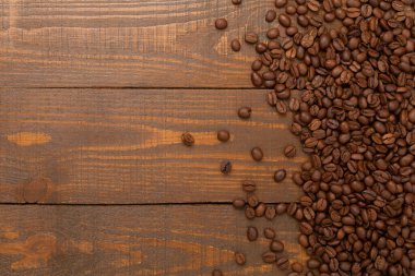 Ahşap arka planda yaprakları olan kavrulmuş kahve çekirdekleri.