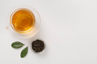 Renkli arka planda kuru ve taze yapraklı bir fincan çay.