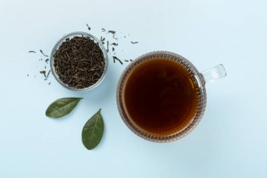 Renkli arka planda kuru ve taze yapraklı bir fincan çay.