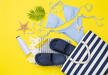 Renkli arka planda yaz aksesuarları olan mavi plaj çantası, üst manzara.