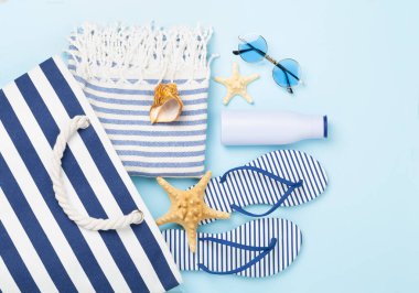 Renkli arka planda yaz aksesuarları olan mavi plaj çantası, üst manzara.