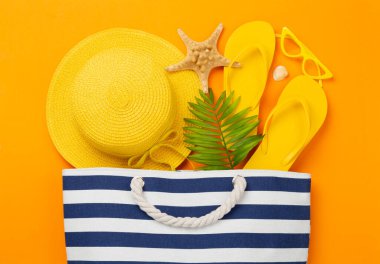 Renkli arka planda yaz aksesuarları olan mavi plaj çantası, üst manzara.