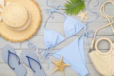 Ahşap arka planda plaj aksesuarları olan mavi bikini.
