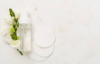 Beton arka planda çiçekli kozmetik şişesi, üst görünüm