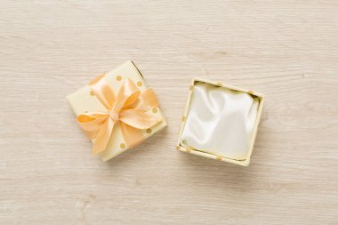 Ahşap zemin üzerinde bej rengi açık hediye kutusu, üst görünüm